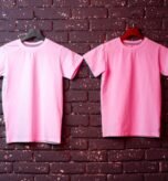 White t-shirt hanging on hanger against brick wall, copy space